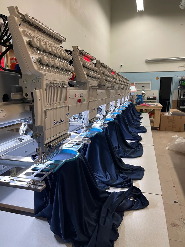 Row of multi-needle embroidery machines stitching navy garments
